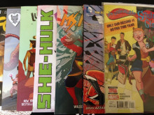 Photograph of seven comic books laid out on top of one another. From bottom to top, they are Faith, Rat Queens, Lumberjanes, She-Hulk, Ms. Marvel, Wonder Woman, and The Unbeatable Squirrel Girl. 
