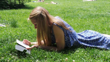 Image of girl reading while laying in the grass.