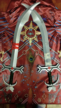 two silver 3D printed cosplay simitar swords lying crossed on a red celestial printed fabric with a peacock feather between their hilts